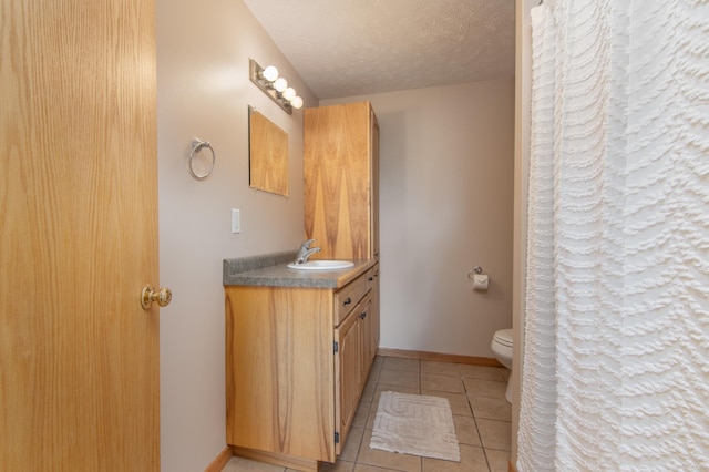 full bathroom with toilet, a textured ceiling, tile patterned flooring, baseboards, and vanity