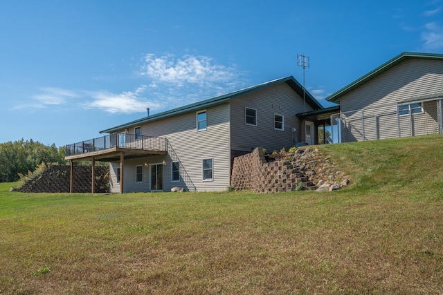 rear view of house featuring a wooden deck and a yard