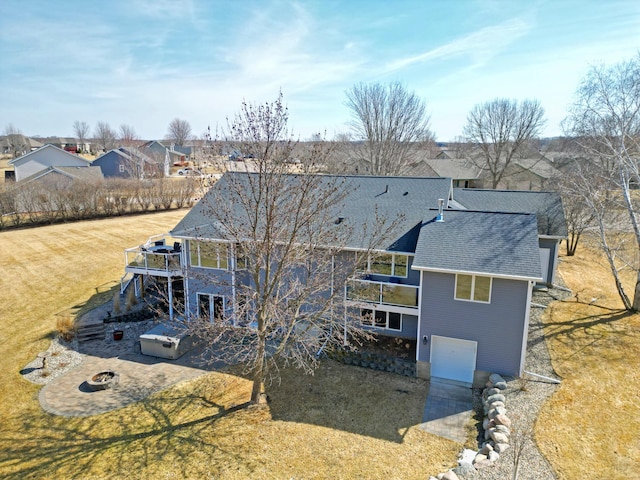 rear view of house featuring a residential view, an attached garage, a yard, and roof with shingles