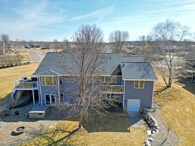 back of house with a wooden deck, a yard, roof with shingles, and an attached garage