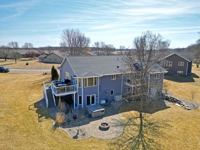 rear view of property with a wooden deck, a yard, stairs, a fire pit, and a patio area