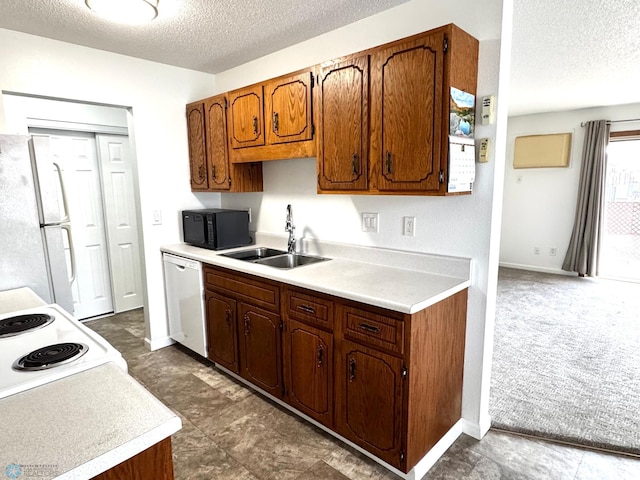 kitchen with dark carpet, light countertops, white appliances, a textured ceiling, and a sink