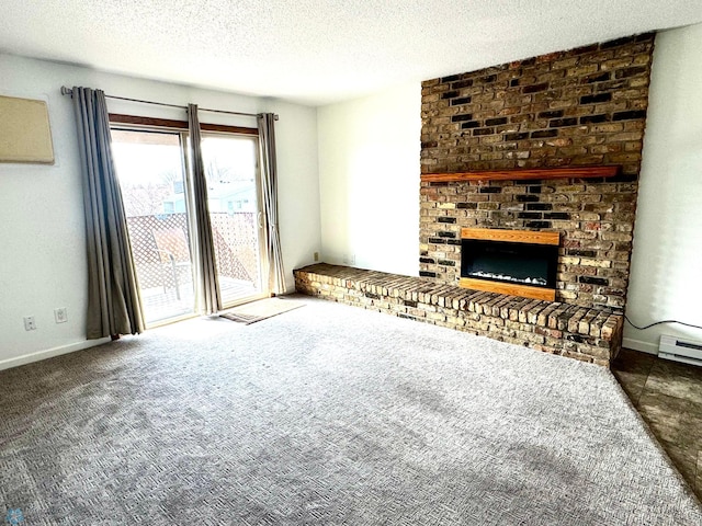 unfurnished living room with a brick fireplace, a textured ceiling, a baseboard heating unit, and carpet