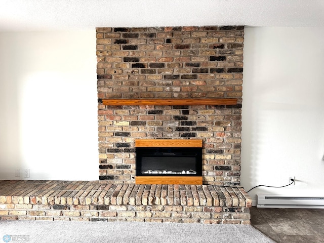 room details featuring a textured ceiling, a brick fireplace, and a baseboard radiator