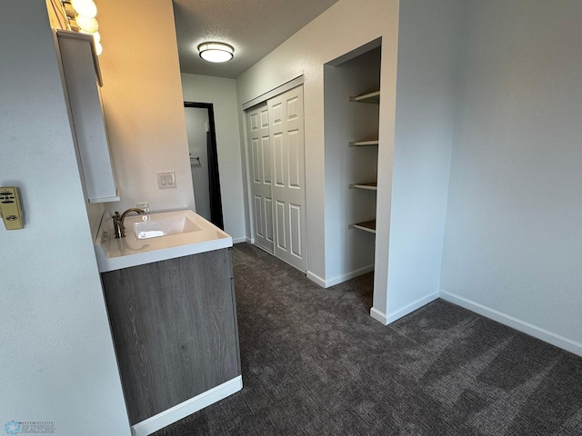 bathroom featuring built in shelves, a textured ceiling, vanity, and baseboards