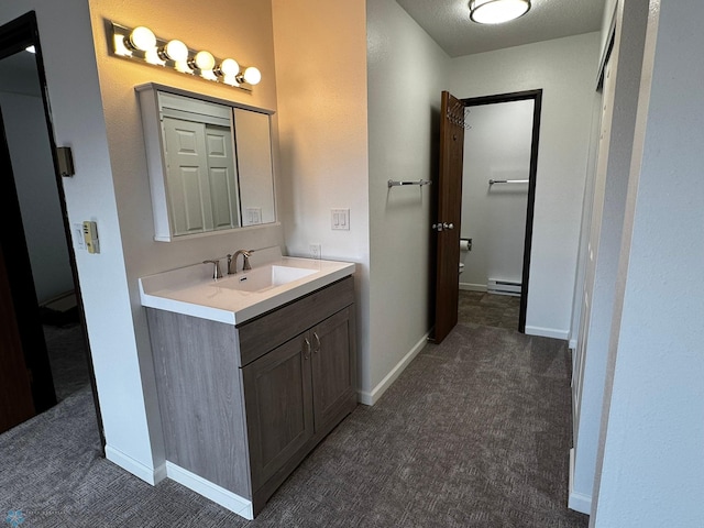 bathroom with a baseboard heating unit, vanity, and baseboards