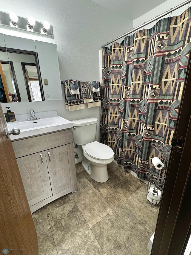 bathroom featuring toilet, vanity, and a shower with curtain