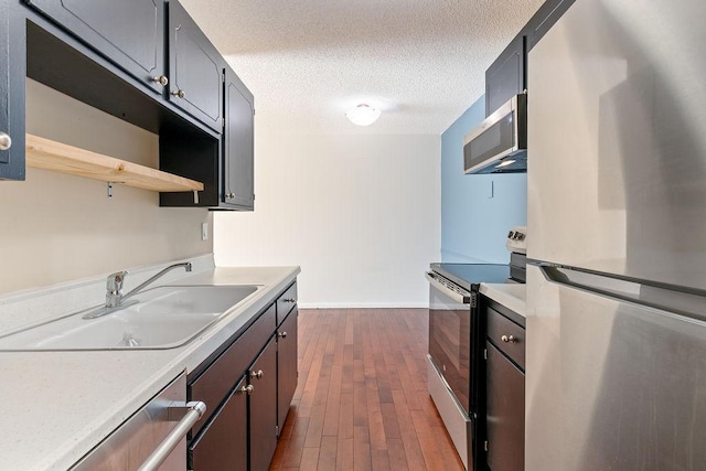 kitchen with dark wood-style flooring, a sink, stainless steel appliances, light countertops, and a textured ceiling