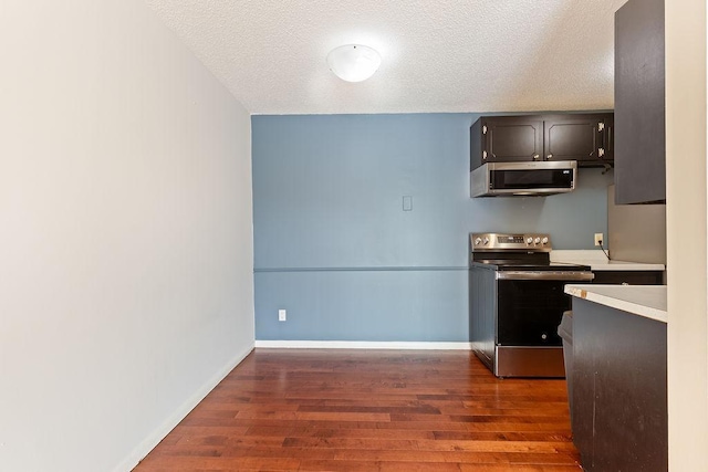 kitchen with light countertops, dark wood-style floors, baseboards, and appliances with stainless steel finishes