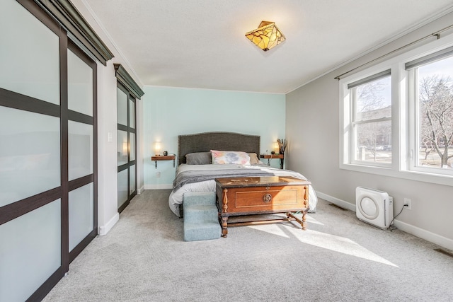 carpeted bedroom with visible vents, baseboards, and ornamental molding