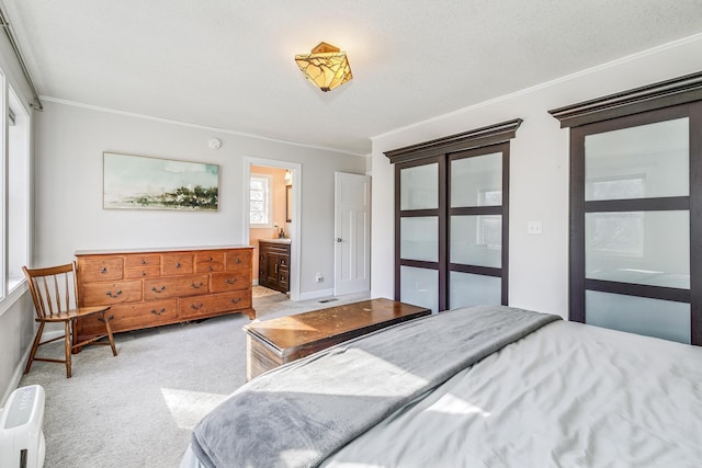 carpeted bedroom featuring baseboards, ensuite bathroom, and ornamental molding