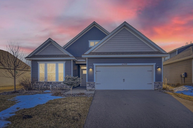 craftsman house with board and batten siding, a garage, stone siding, and driveway