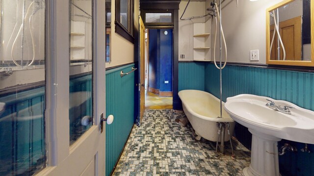 bathroom with a sink, a soaking tub, and wainscoting