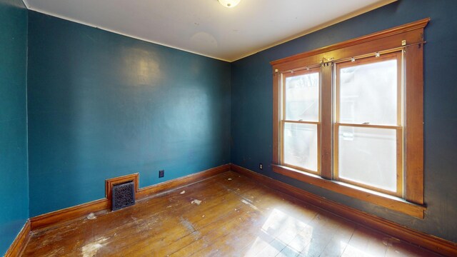 spare room featuring baseboards, visible vents, and hardwood / wood-style floors