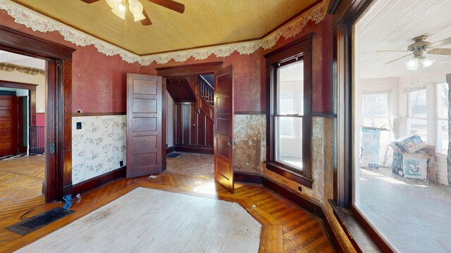 interior space with wallpapered walls, visible vents, ceiling fan, and wainscoting