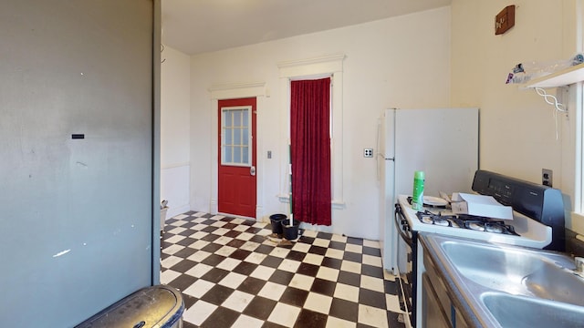 kitchen with tile patterned floors, a sink, and white gas stove