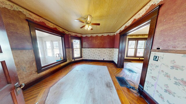 spare room featuring a wainscoted wall, a wealth of natural light, wallpapered walls, and ceiling fan