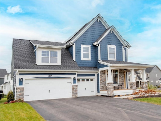 craftsman house featuring driveway, a porch, an attached garage, a shingled roof, and stone siding