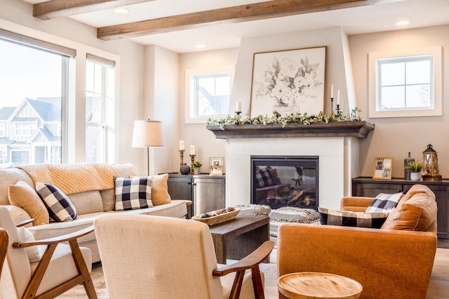 living room featuring light wood-type flooring, beamed ceiling, a glass covered fireplace, and recessed lighting