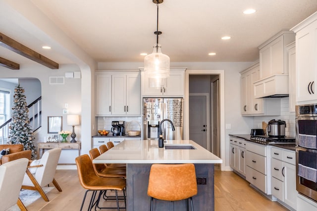 kitchen featuring visible vents, a sink, stainless steel appliances, light wood-style floors, and a breakfast bar area