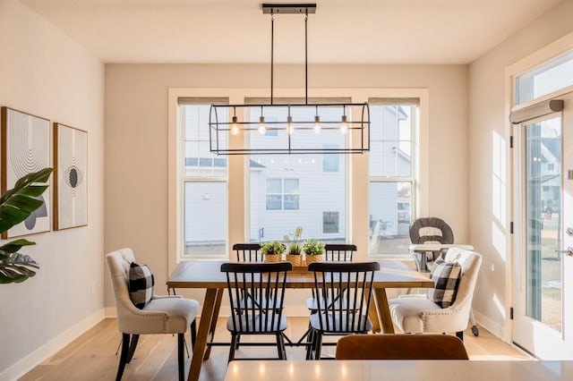dining space with baseboards, an inviting chandelier, and wood finished floors