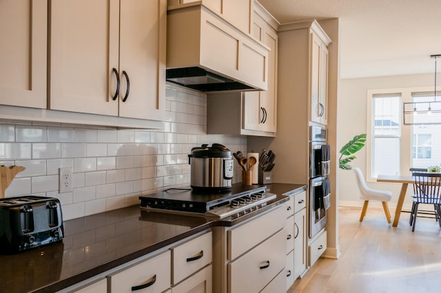 kitchen featuring dark countertops, backsplash, stainless steel appliances, light wood-style floors, and custom exhaust hood