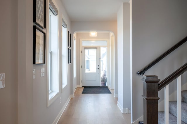 doorway to outside featuring stairs, wood finished floors, baseboards, and arched walkways