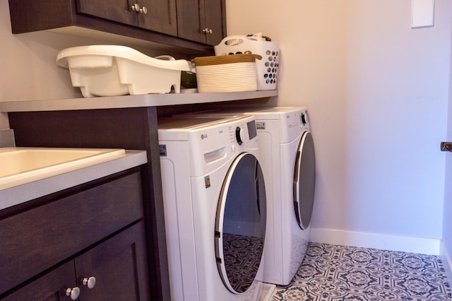 laundry area featuring light tile patterned floors, washing machine and dryer, cabinet space, and baseboards