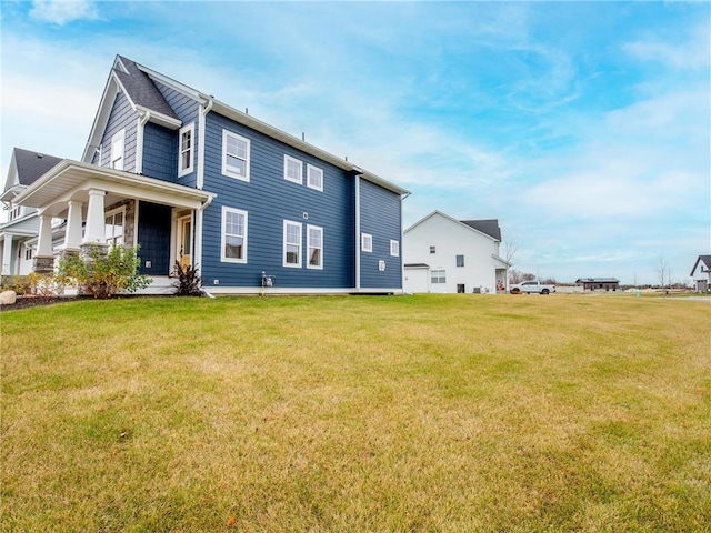 rear view of house featuring a lawn and covered porch