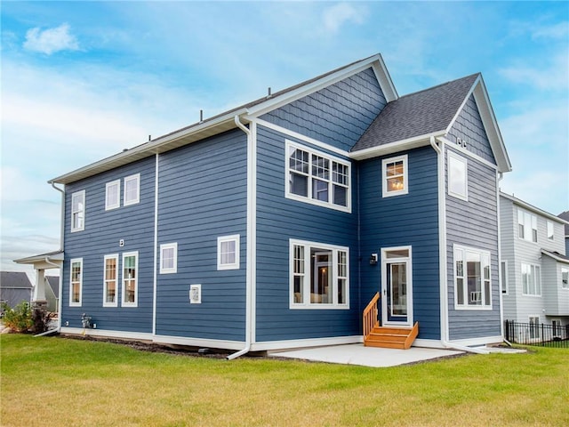 rear view of property featuring fence, a lawn, entry steps, and a patio area
