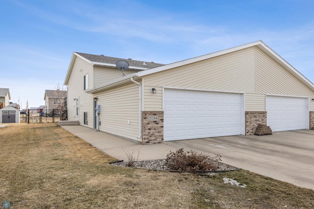 view of side of property featuring an outbuilding, concrete driveway, and fence