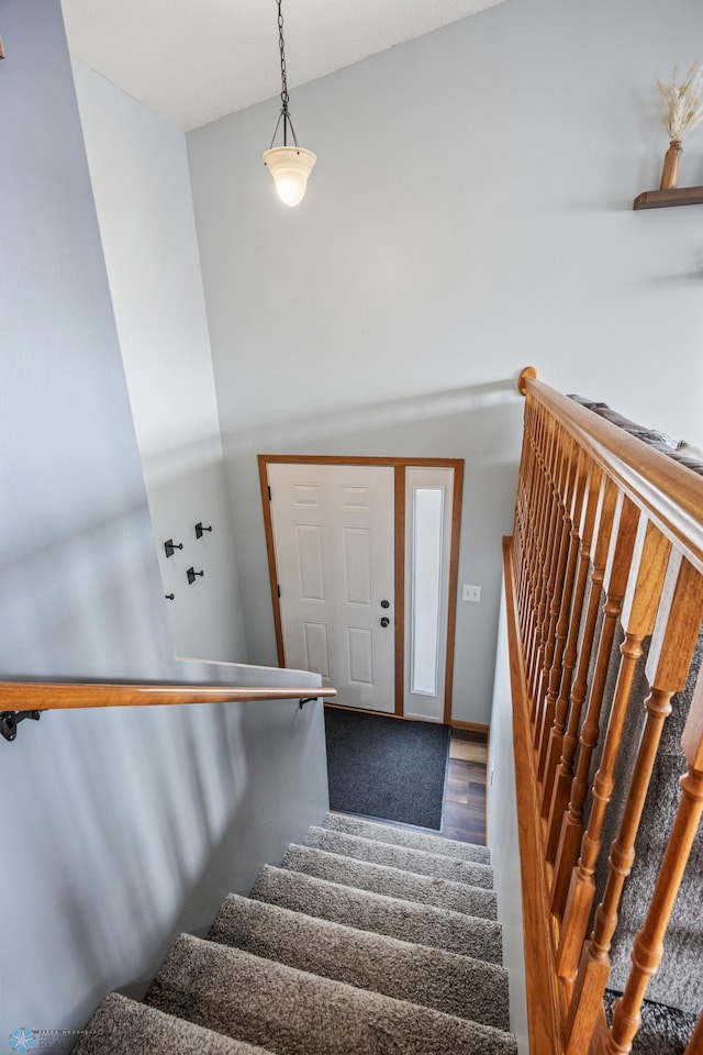 stairs with a high ceiling and wood finished floors