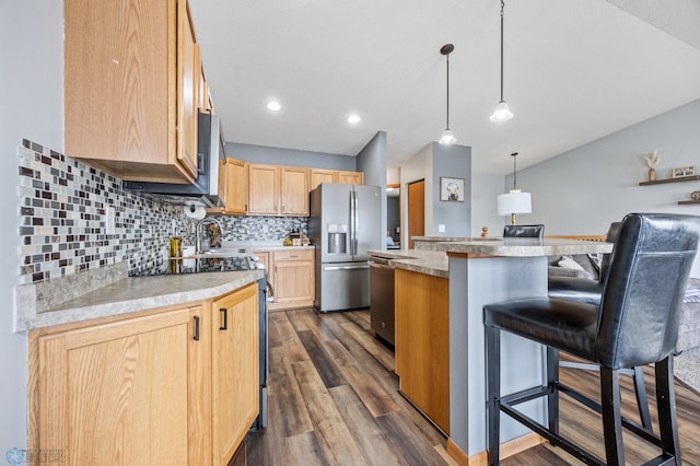 kitchen featuring a center island, light brown cabinetry, dark wood finished floors, a breakfast bar, and appliances with stainless steel finishes