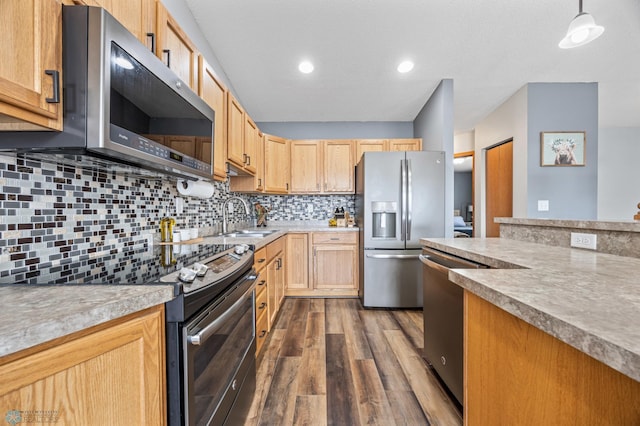 kitchen featuring tasteful backsplash, dark wood finished floors, light countertops, appliances with stainless steel finishes, and a sink