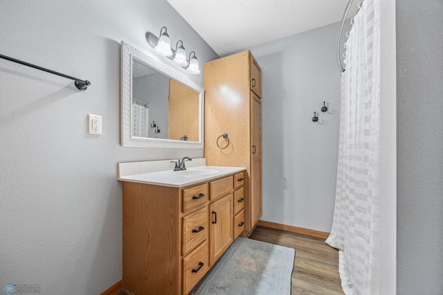 bathroom with vanity, curtained shower, wood finished floors, and baseboards