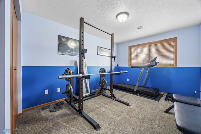 workout room with a textured ceiling, baseboards, and carpet floors