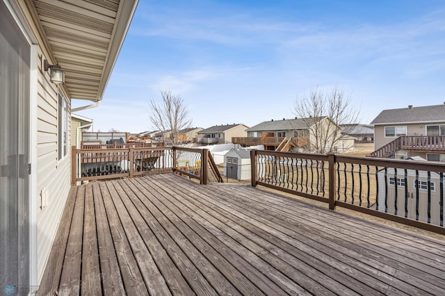 deck with a residential view, a storage shed, and an outdoor structure