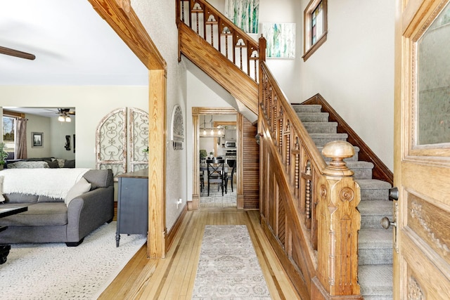 staircase featuring a ceiling fan and wood-type flooring