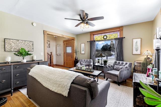 living area with stairway, light wood-type flooring, and ceiling fan