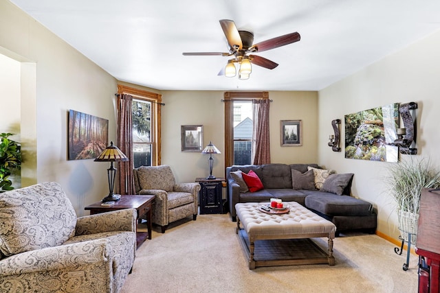 living area with a ceiling fan, light colored carpet, and a healthy amount of sunlight