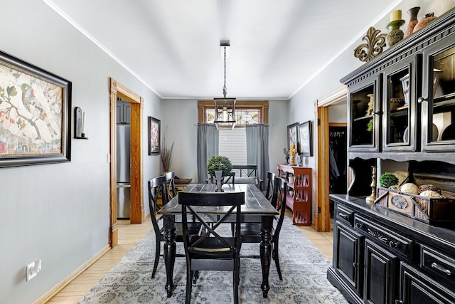 dining room featuring a notable chandelier, light wood-type flooring, crown molding, and baseboards