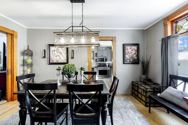 dining space featuring light wood-style floors and ornamental molding