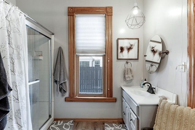 full bath featuring baseboards, vanity, wood finished floors, and a shower stall