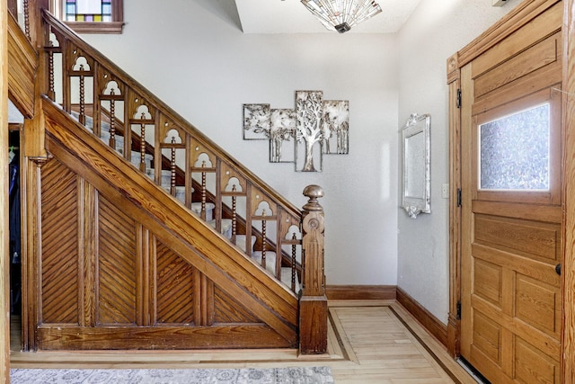 foyer entrance featuring light wood-style floors, plenty of natural light, stairs, and baseboards