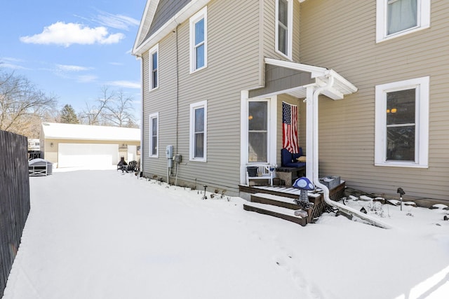 view of snowy exterior featuring an outbuilding and a garage