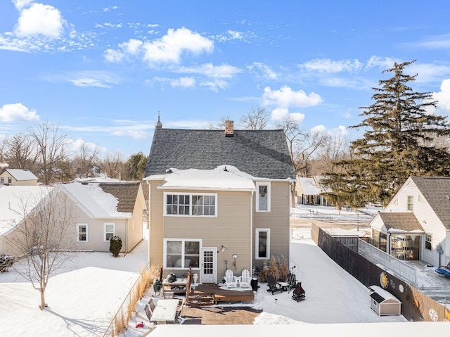 back of house featuring a deck, roof with shingles, a fenced backyard, and a chimney