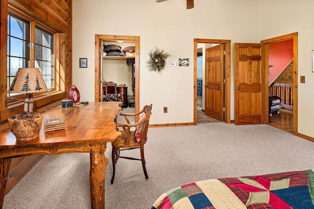 interior space with baseboards, a ceiling fan, and a towering ceiling