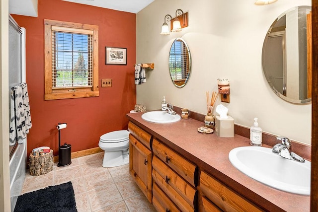 full bathroom with a sink, toilet, double vanity, and tile patterned floors