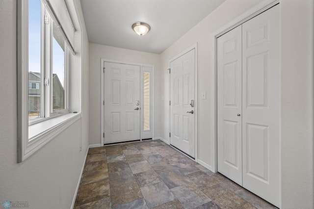 foyer with baseboards and stone finish floor