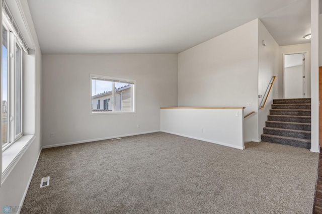 unfurnished room featuring visible vents, lofted ceiling, carpet, and baseboards